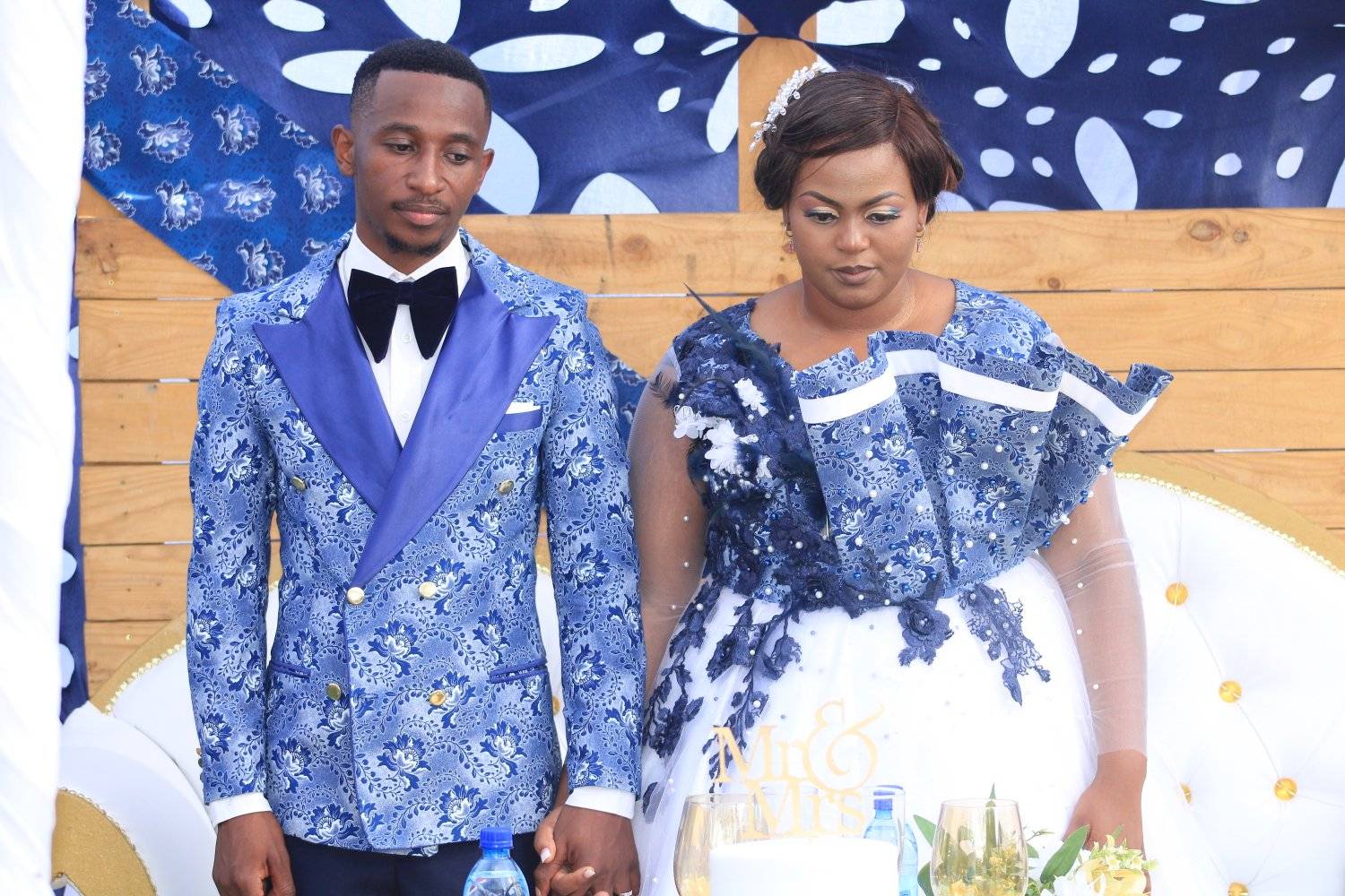 A couple in matching blue and white outfits holding hands at their wedding celebration