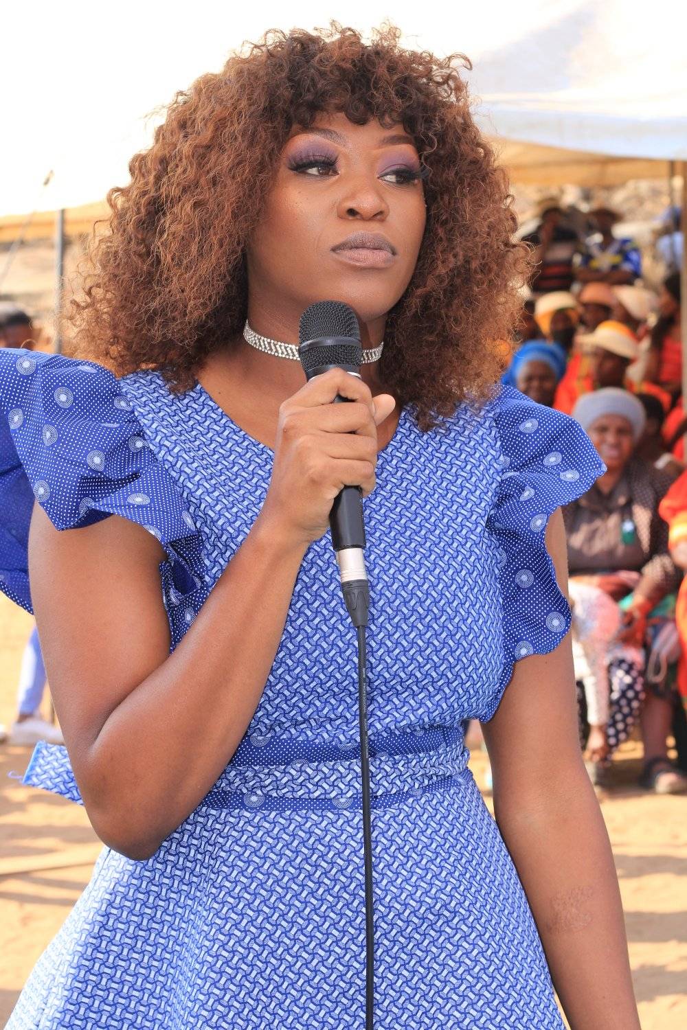 A woman speaking into a microphone at an outdoor gathering