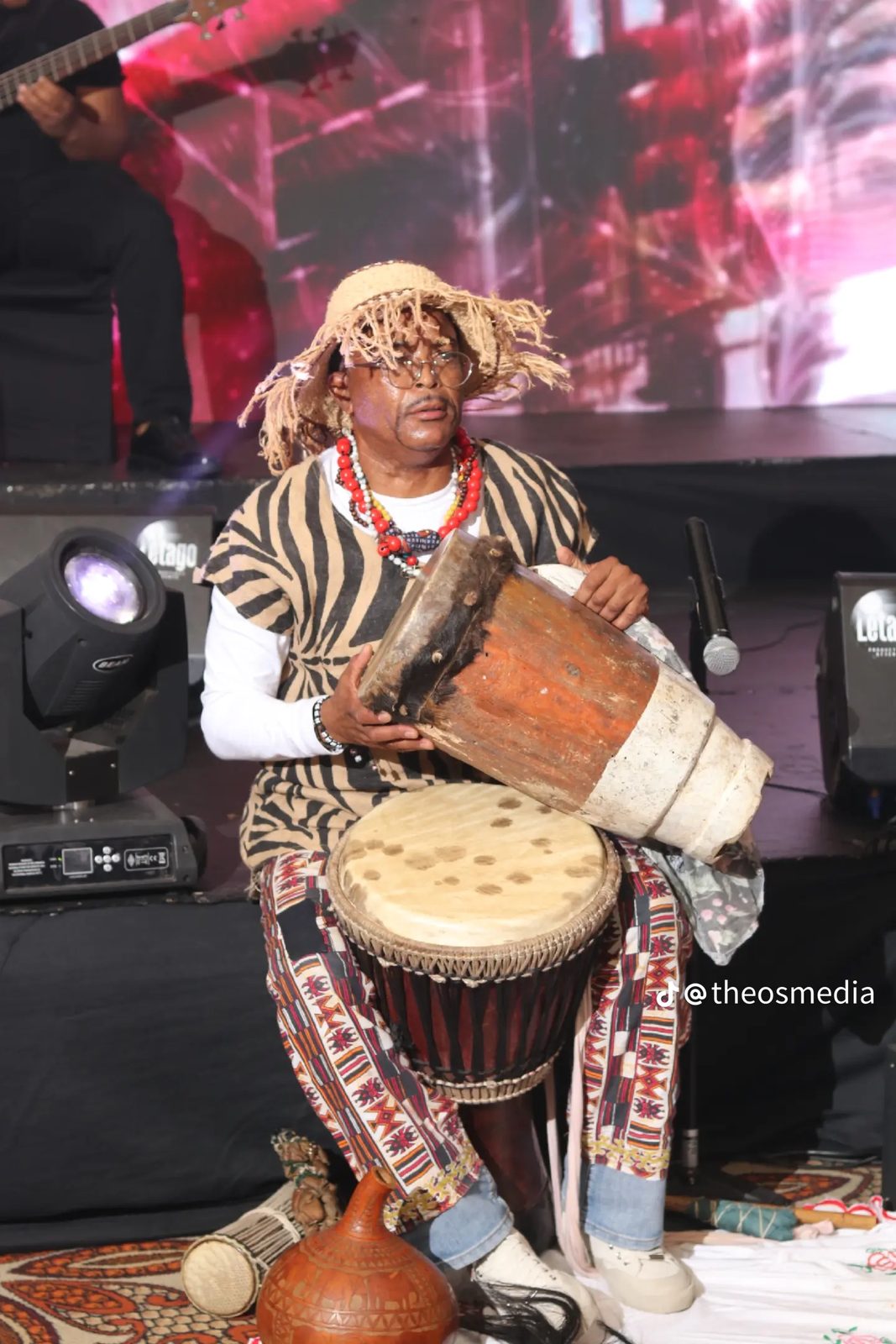 A musician playing traditional drums on a lit stage