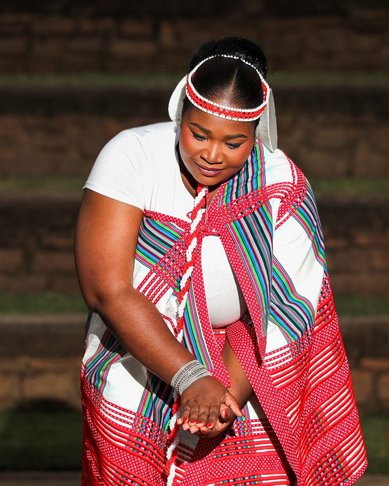 A woman in a red and white traditional outfit looking down at her hands