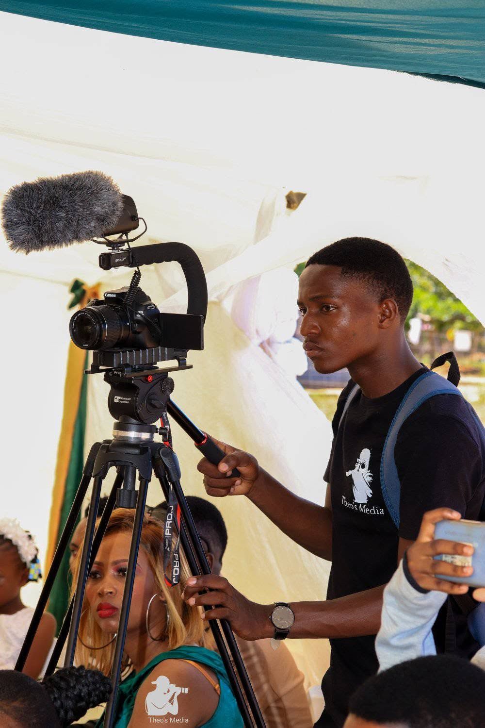 The founder filming under a tent at an outdoor celebration